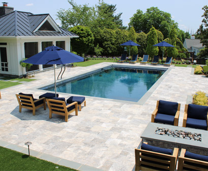 A luxury poolside area complete with lounge chairs and umbrellas for pool-deck-ideas blog.